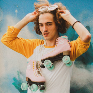 Lifestyle shot of the BTFL Ava Pro Roller skate hanging around neck of man with cupcake sun glasses